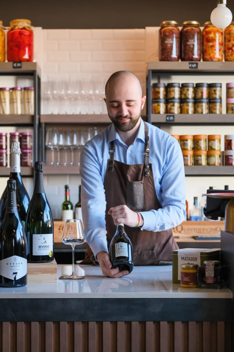 Interni ENOè con sommelier e bottiglie di vino in primo piano
